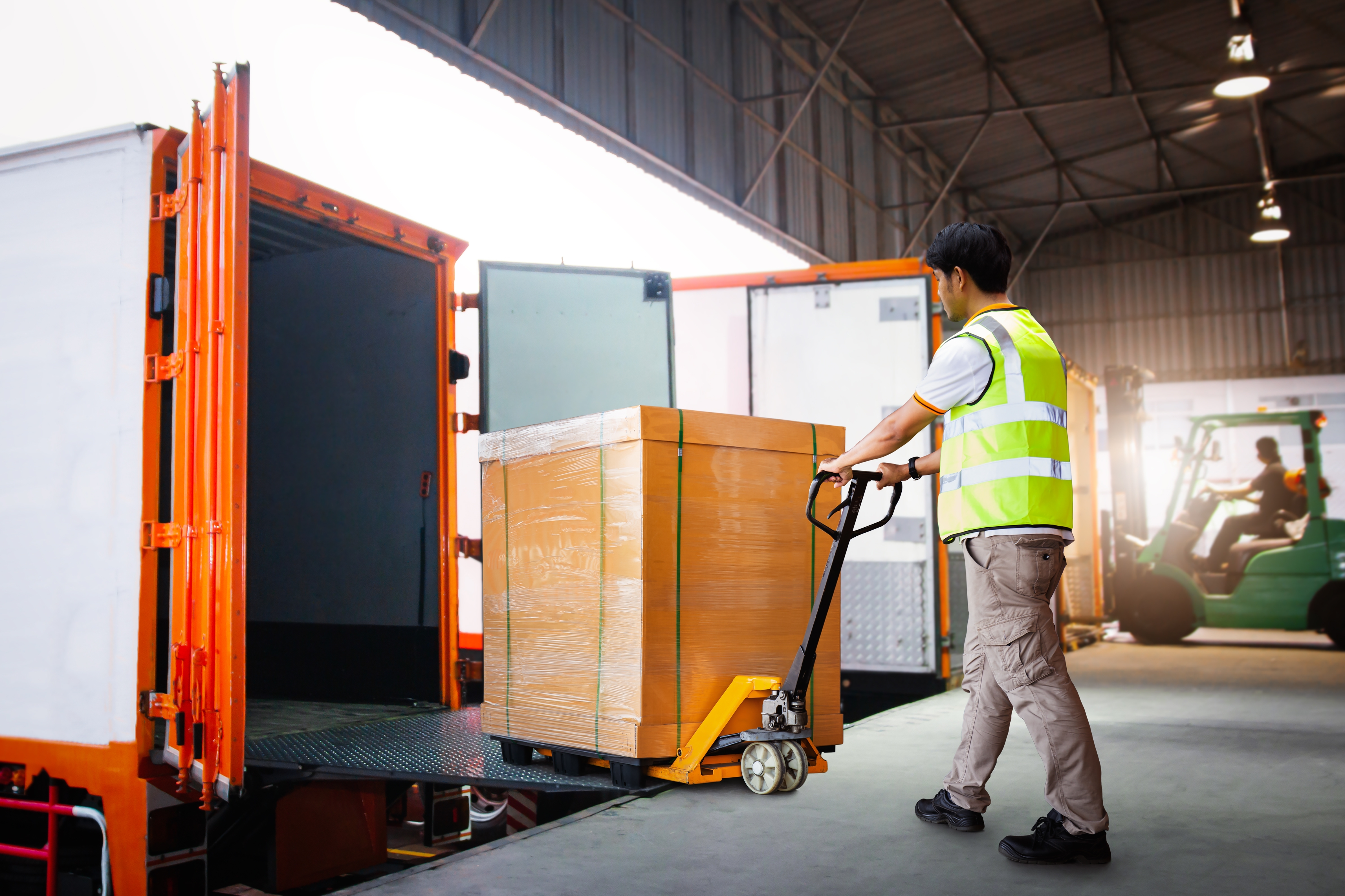 Man using a pallet jack to load an e-commerce product order onto a truck for delivery