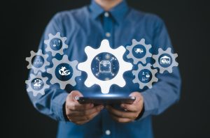 Businessperson using digital tablet with logistics icons overlaid, representing automation and supply chain technology integration